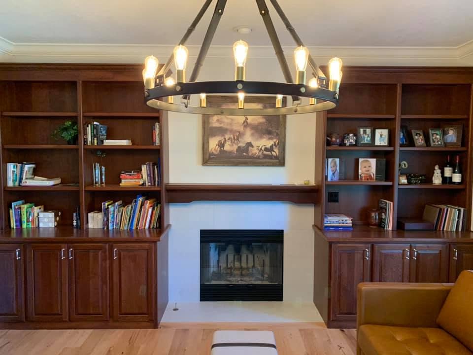 Updated light fireplace surround between dark wood built-in bookshelves
