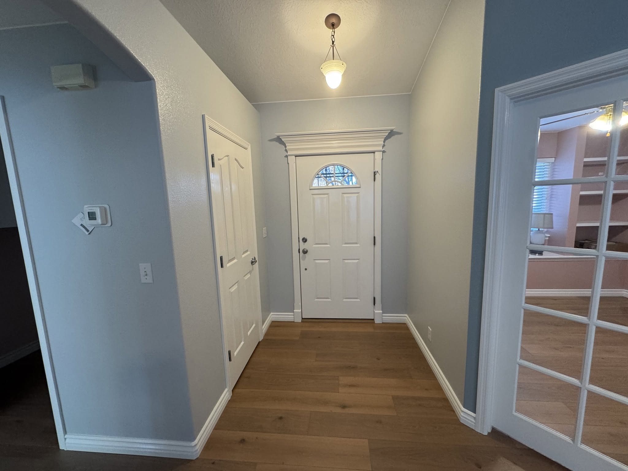 Entry with blue-gray walls, white doors and trim, and wood flooring.